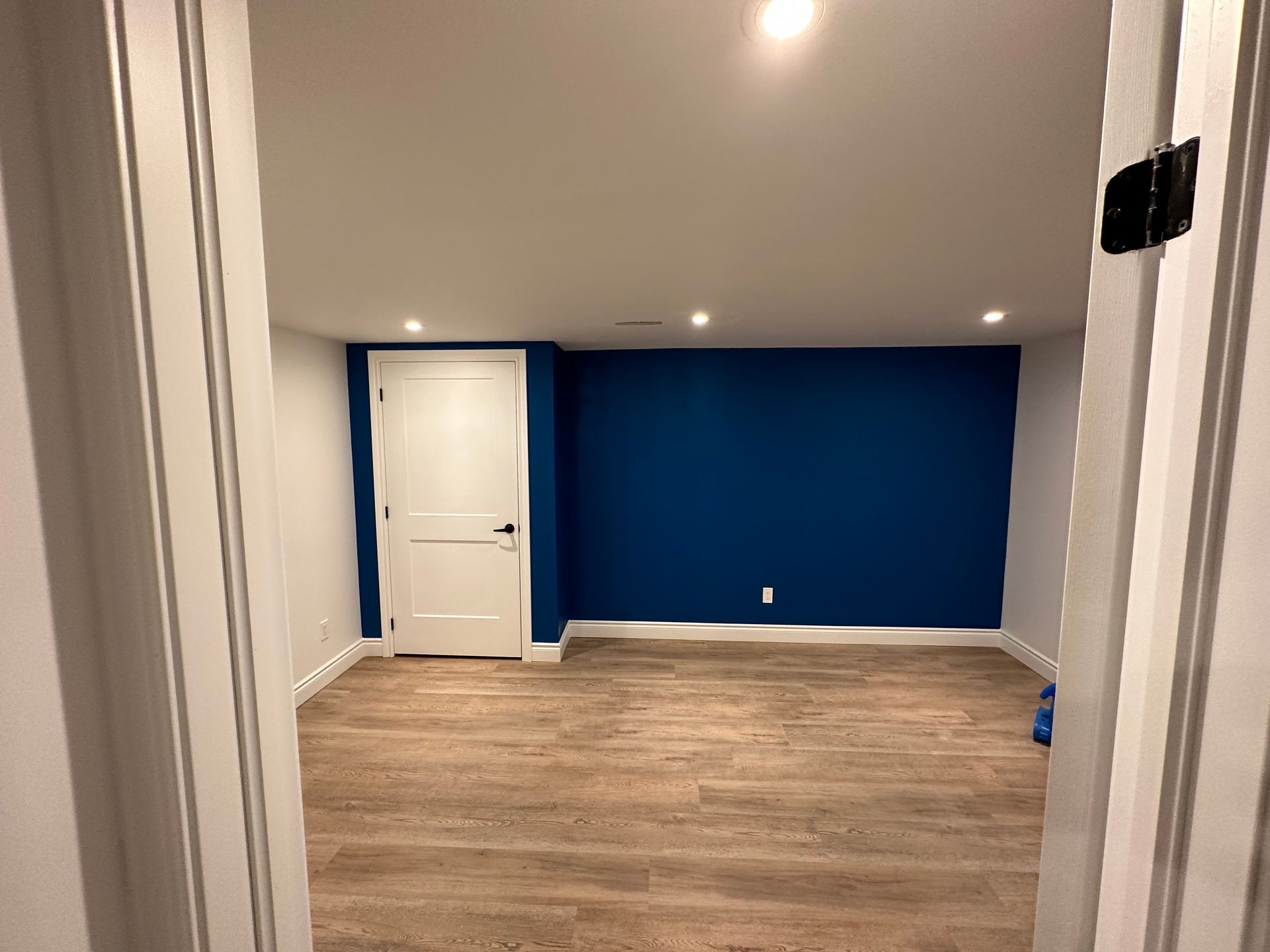 An empty room with blue walls and wooden floors.