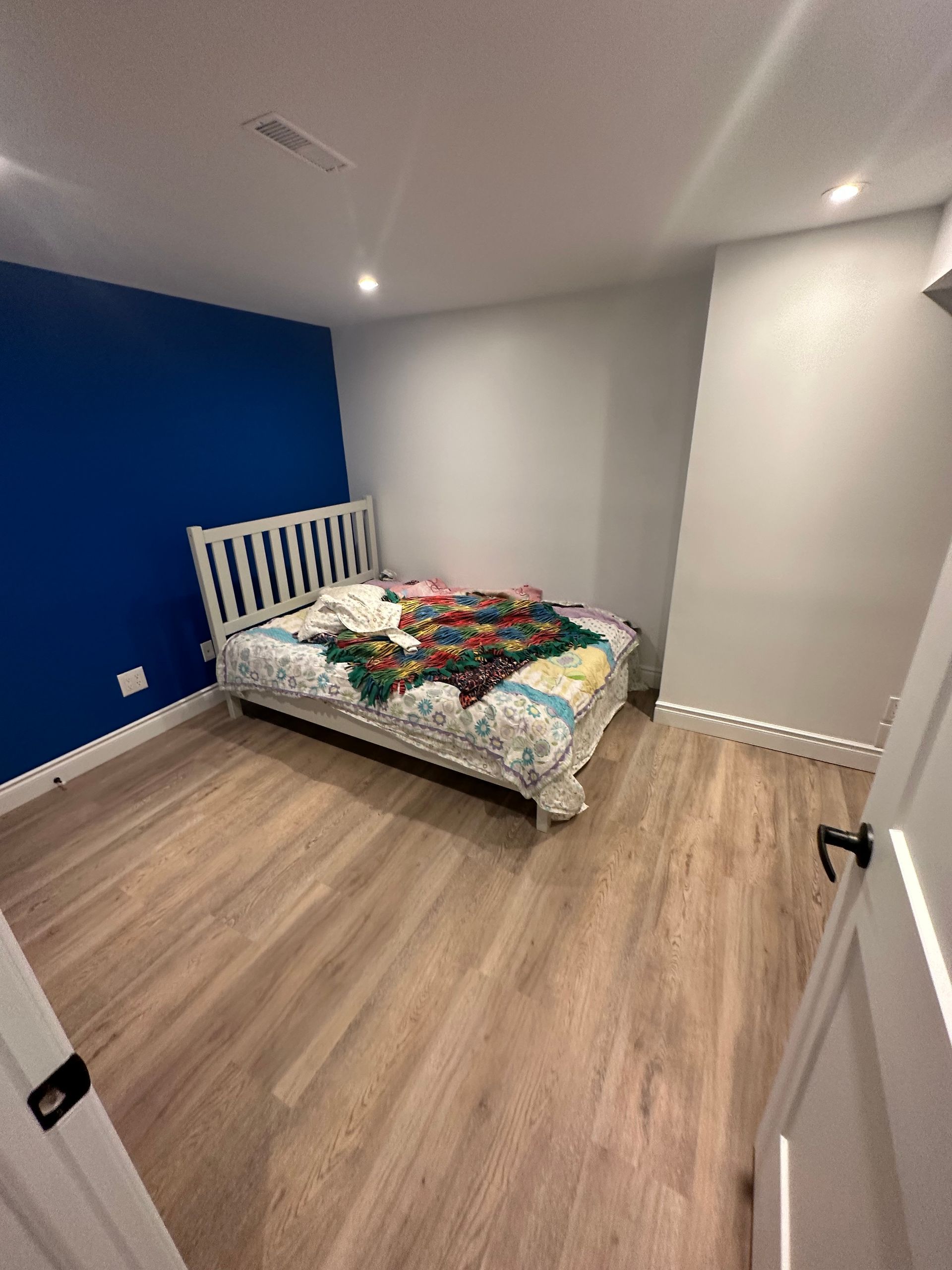 A bedroom with a bed and a blue wall.
