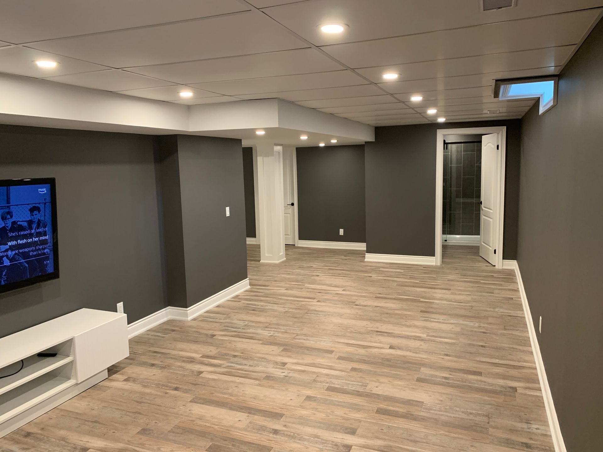 An empty basement with a flat screen tv on the wall.