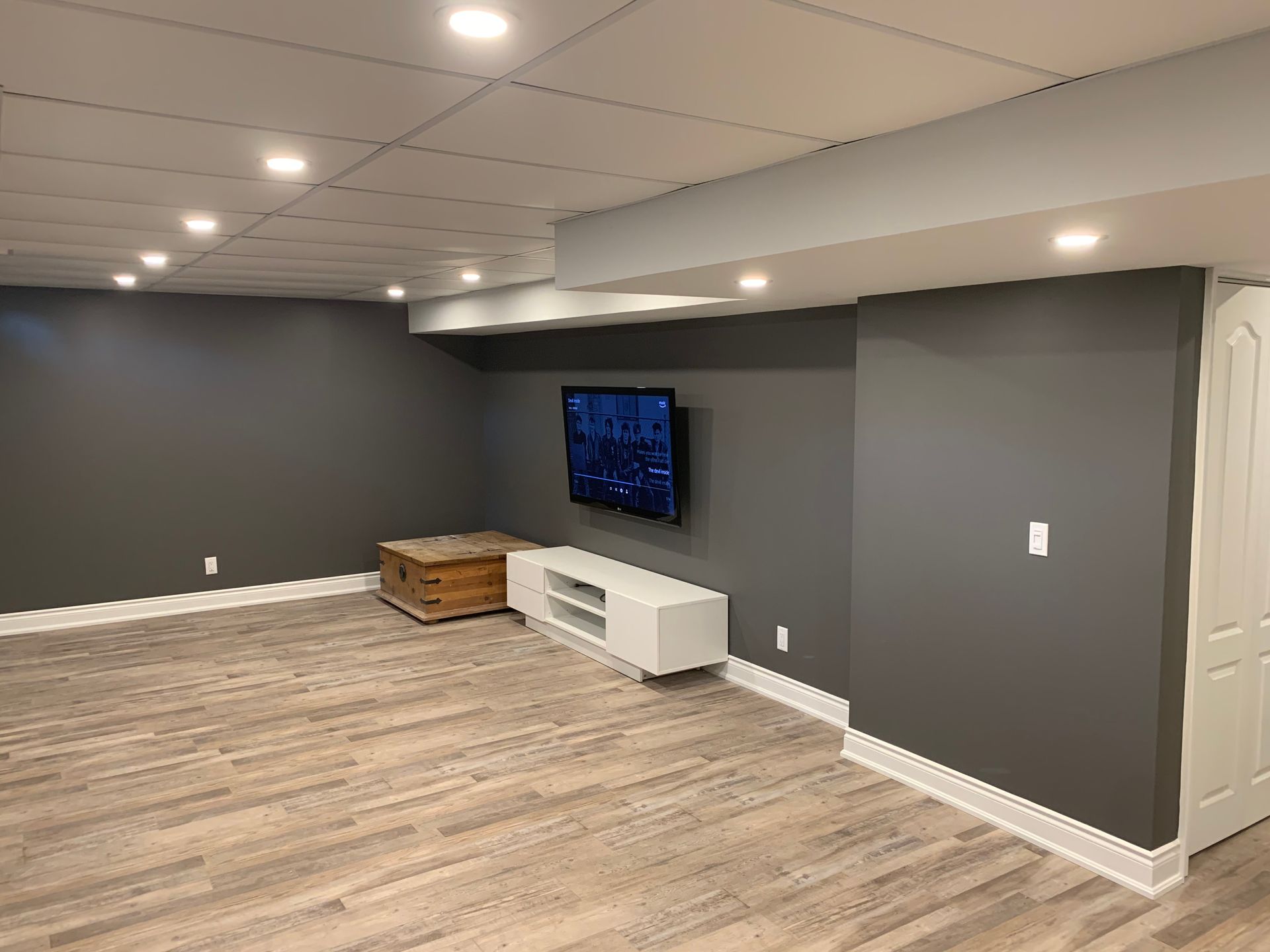 A basement with a flat screen tv mounted on the wall.