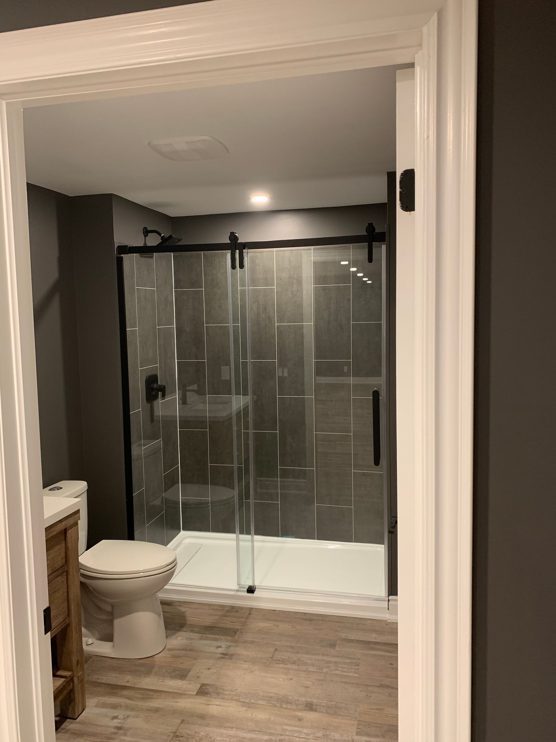 A bathroom with a toilet , sink , shower and sliding glass door.
