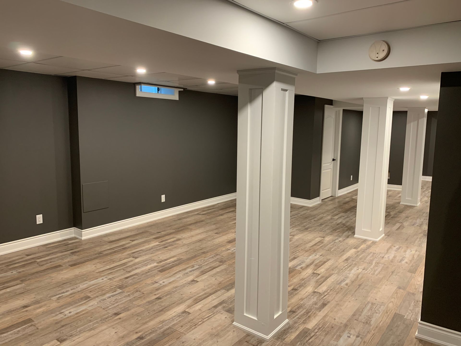 An empty basement with hardwood floors and columns.