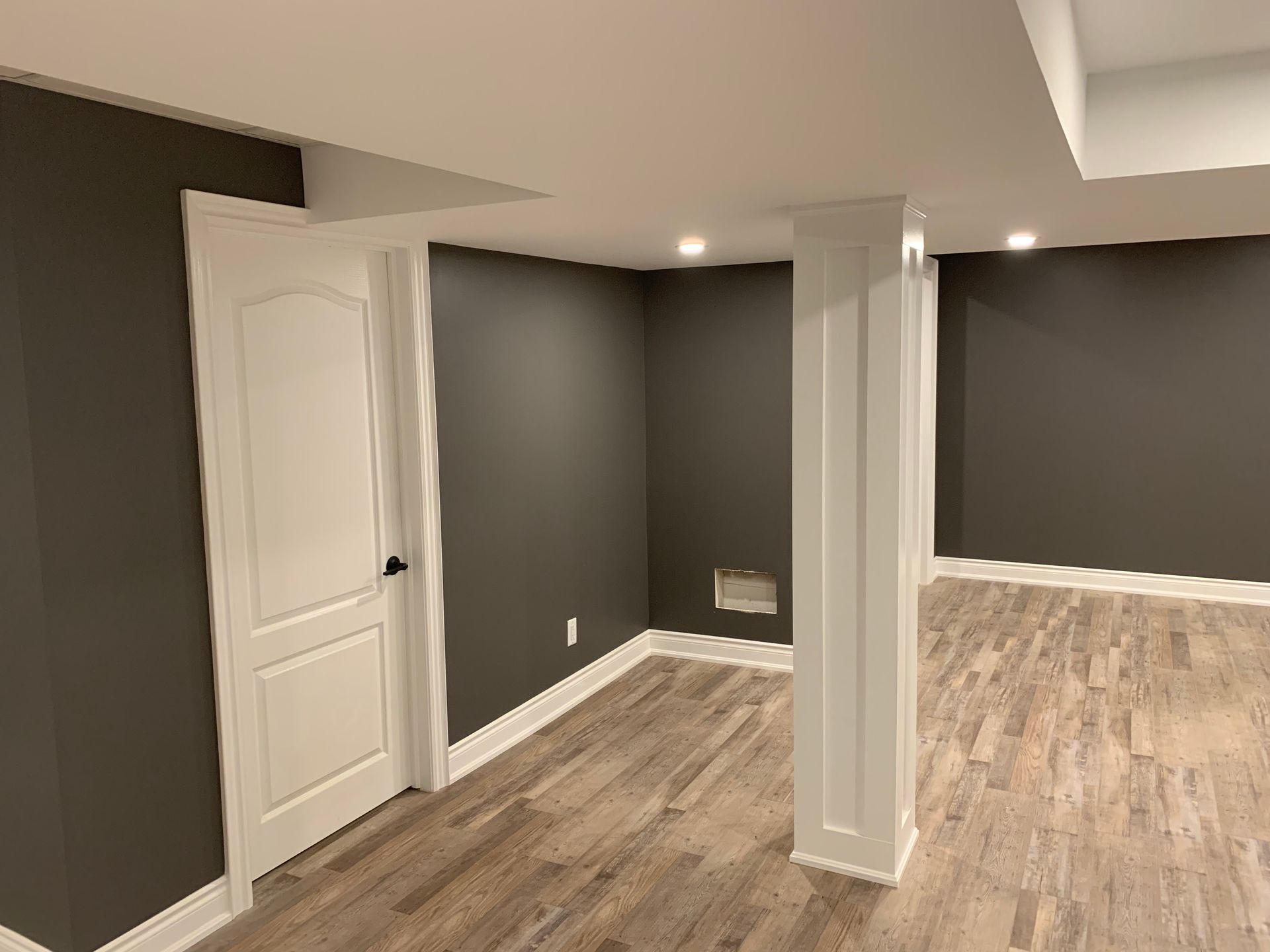 An empty basement with dark walls and wooden floors.