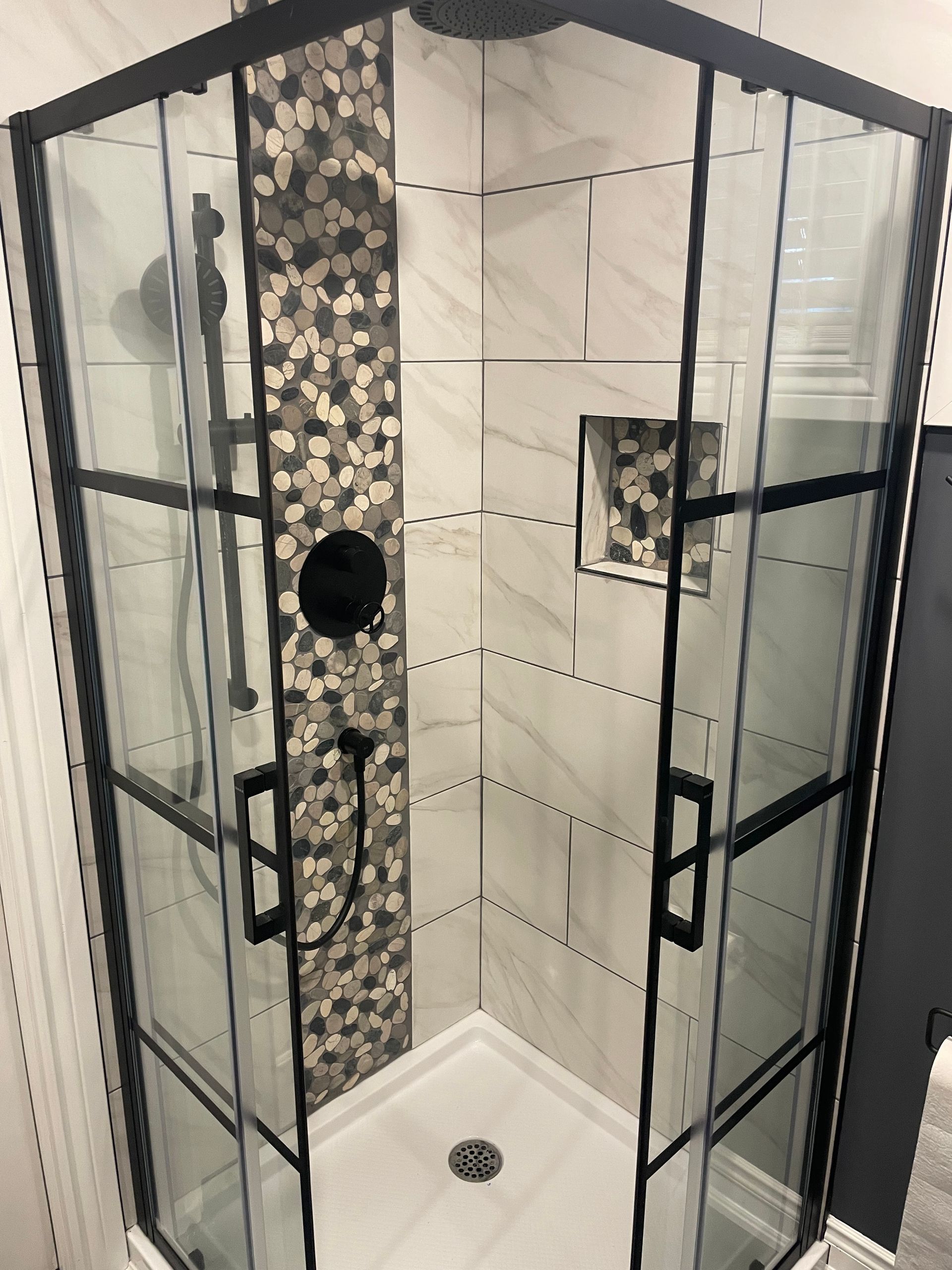 A shower stall with a black frame and clear glass doors.