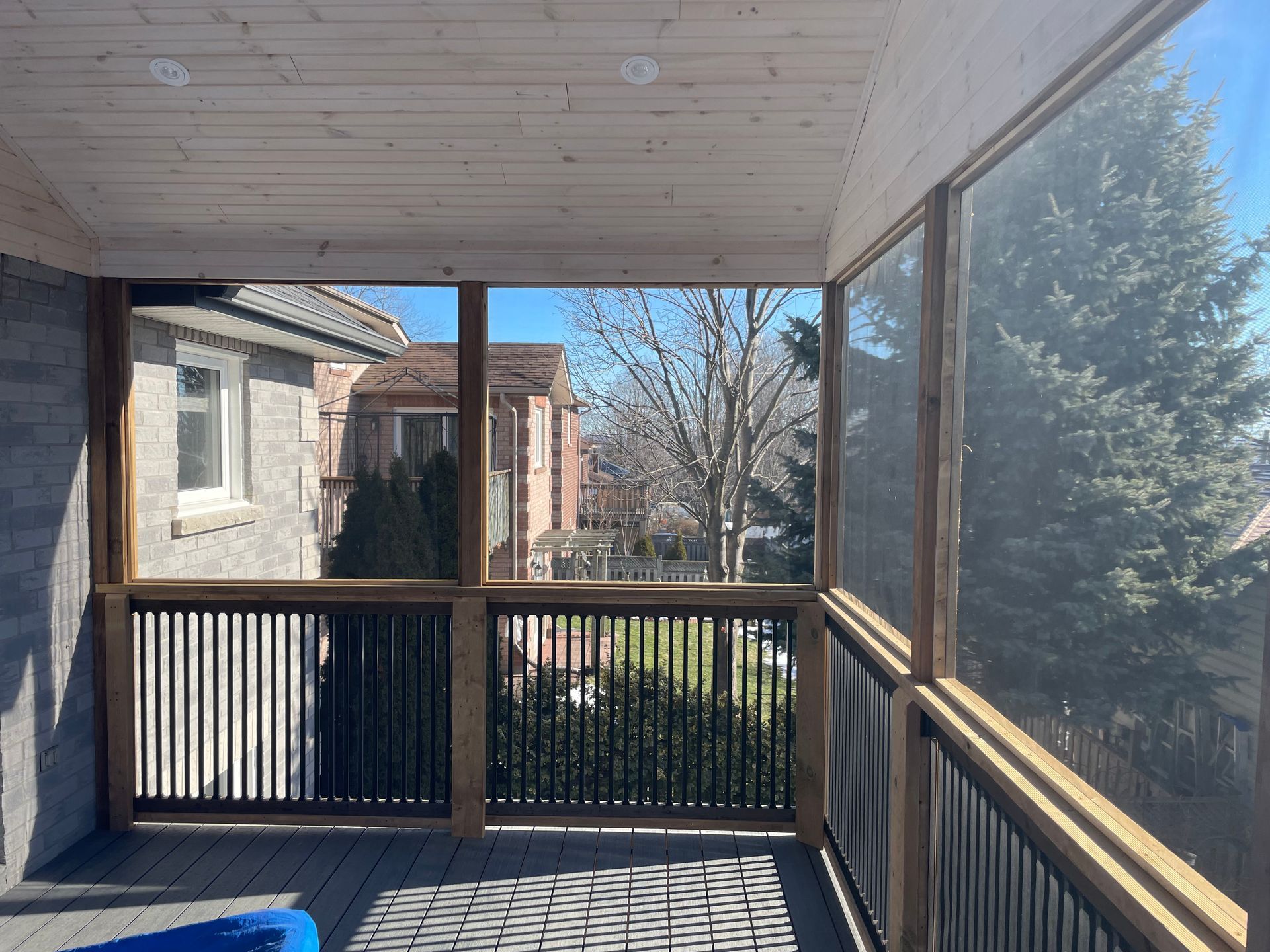 A screened in porch with a view of a house and trees
