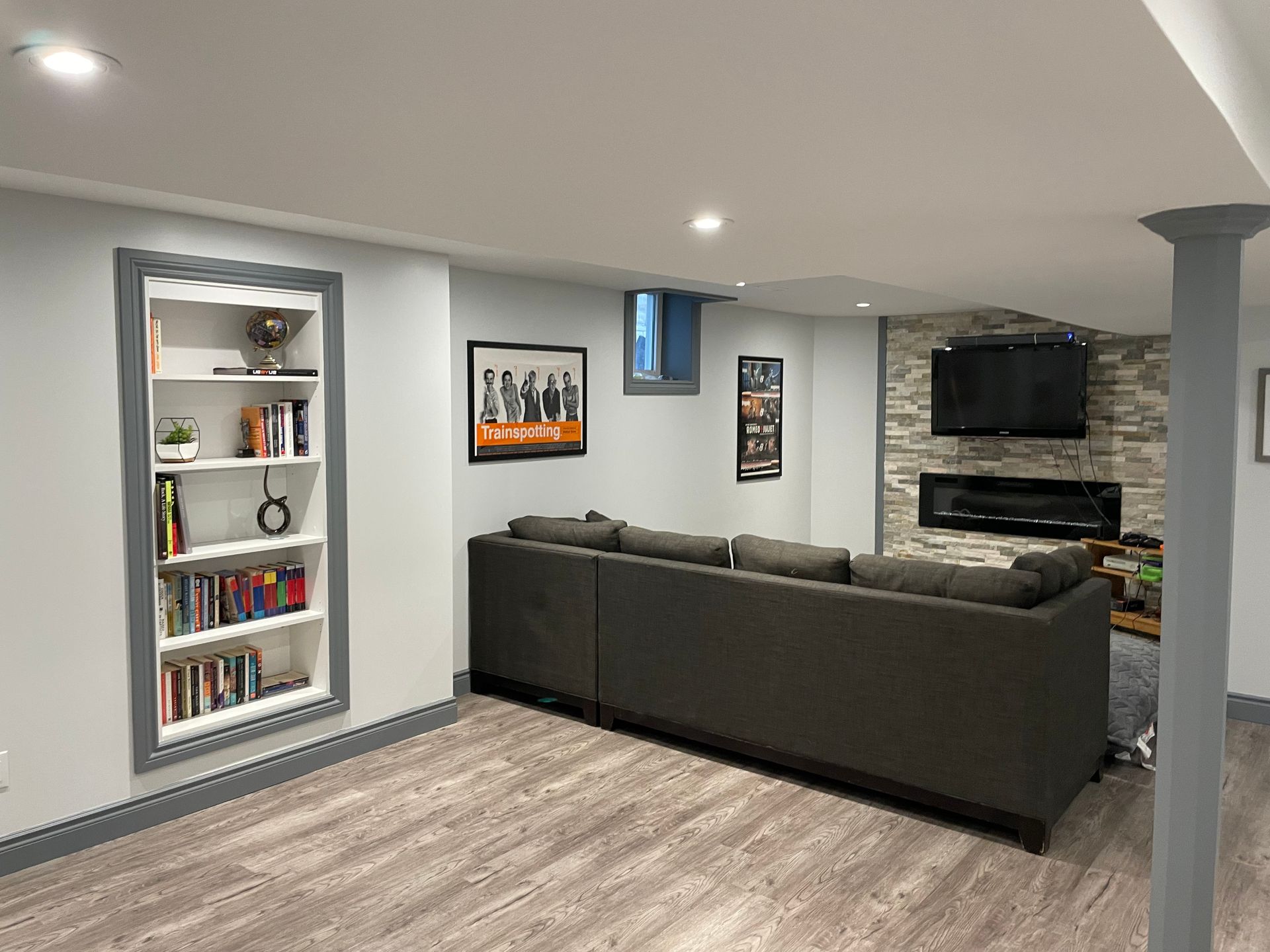 A living room with a couch , bookshelf , television and fireplace.