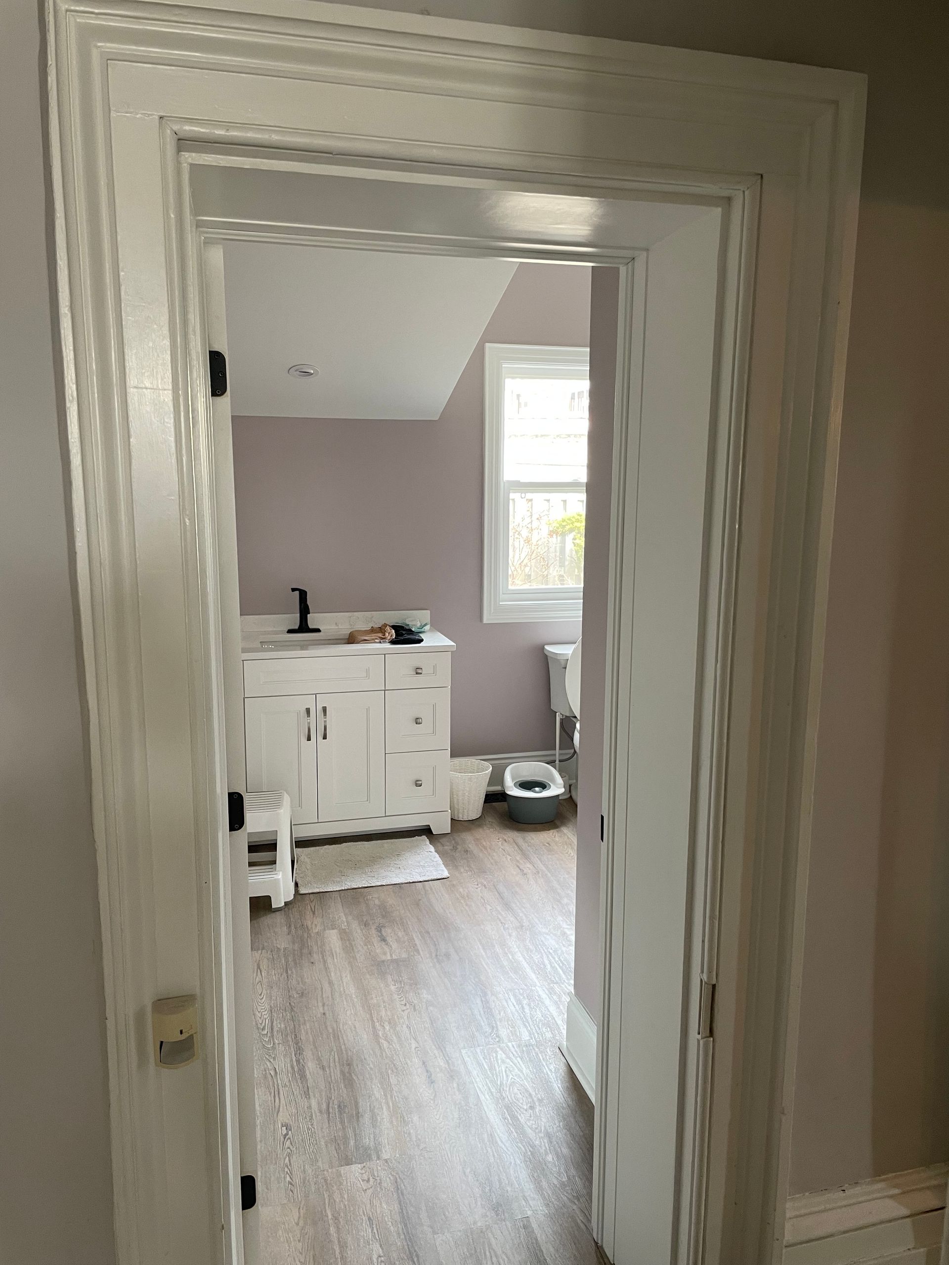 A bathroom with a sink , toilet , and window.