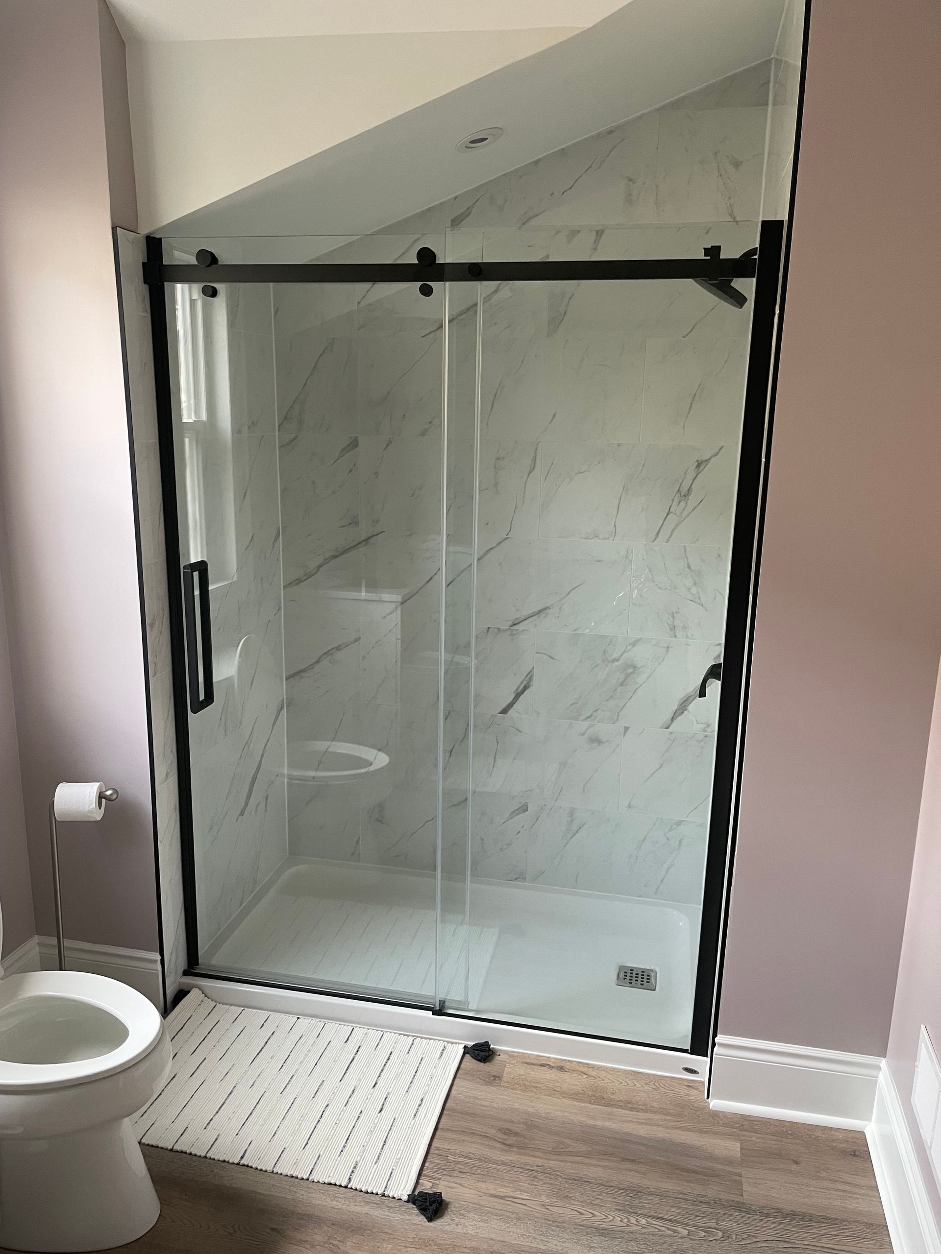 A bathroom with a toilet and a shower with a sliding glass door.