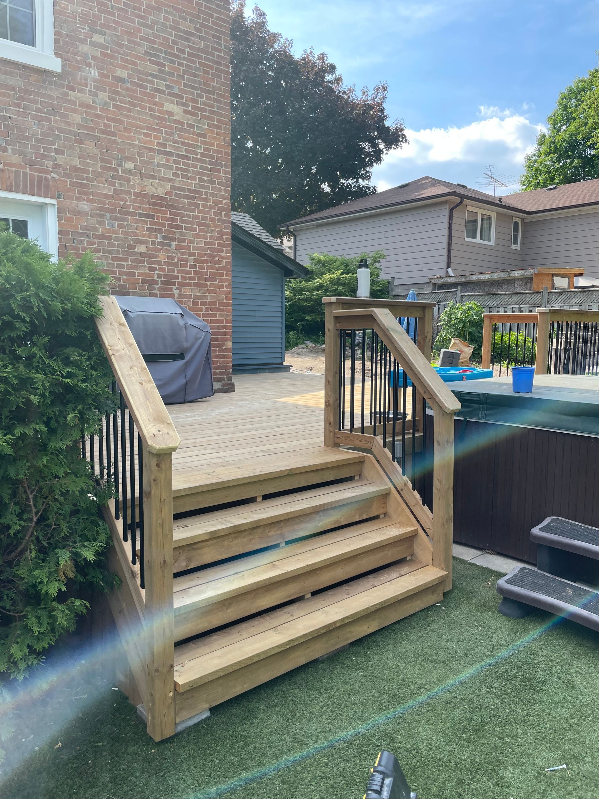 A wooden deck with stairs leading up to it in a backyard.