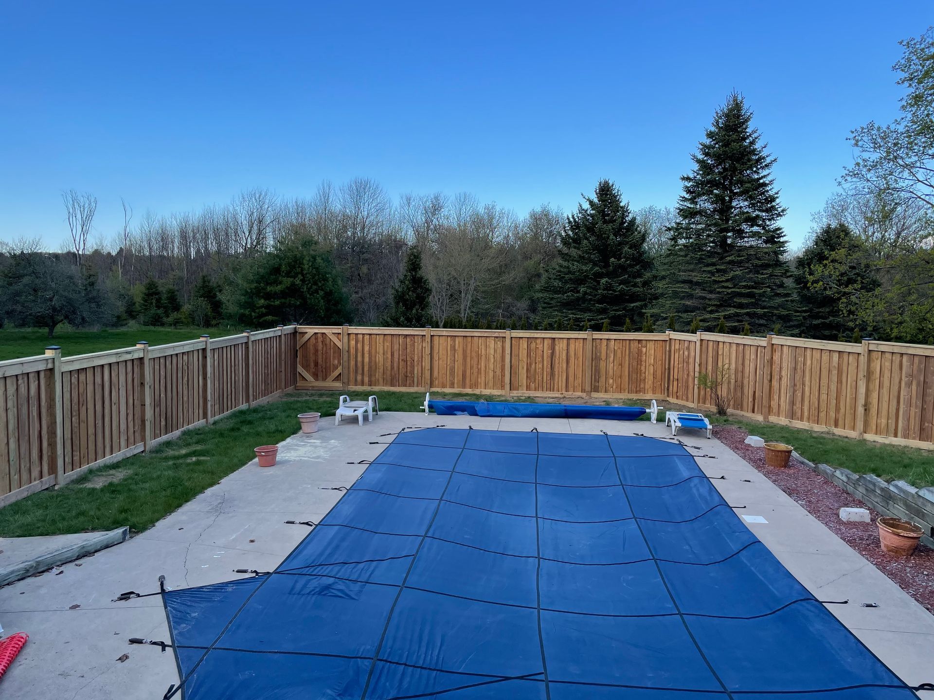 A swimming pool with a blue cover and a wooden fence
