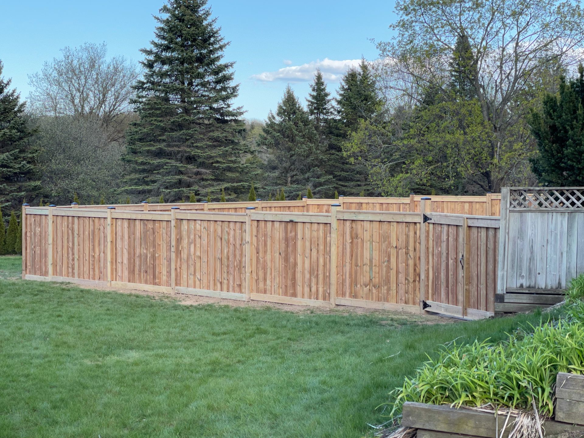 A wooden fence is in the middle of a lush green field.