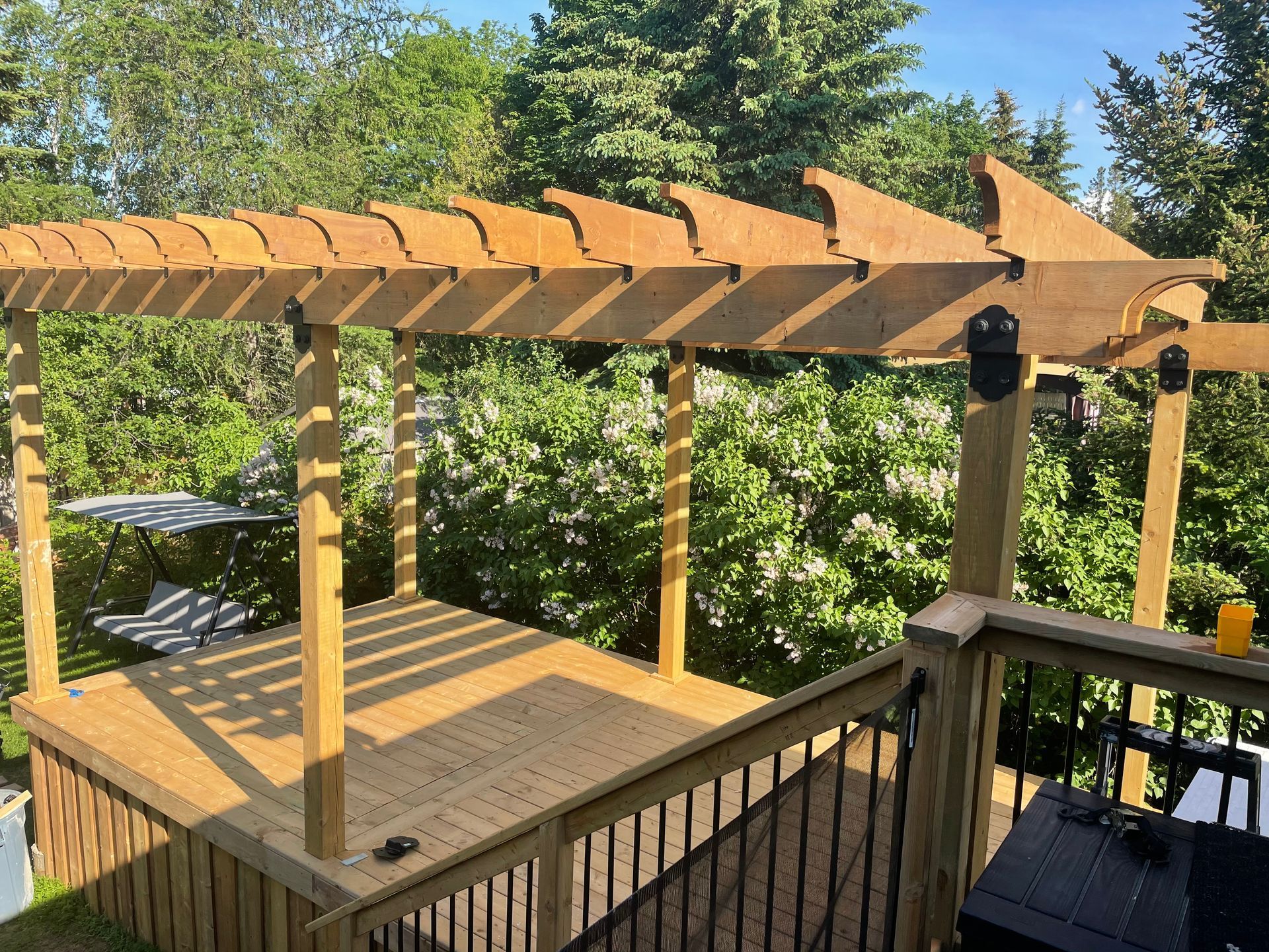 A wooden pergola is sitting on top of a wooden deck.