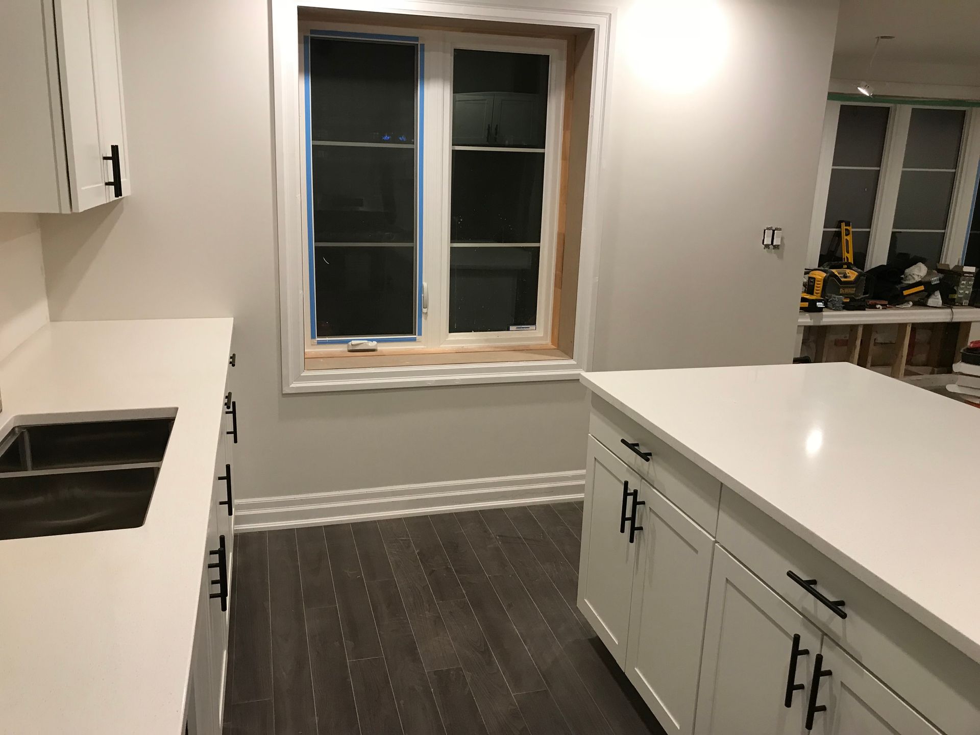 A kitchen with white cabinets , a sink , and a window.