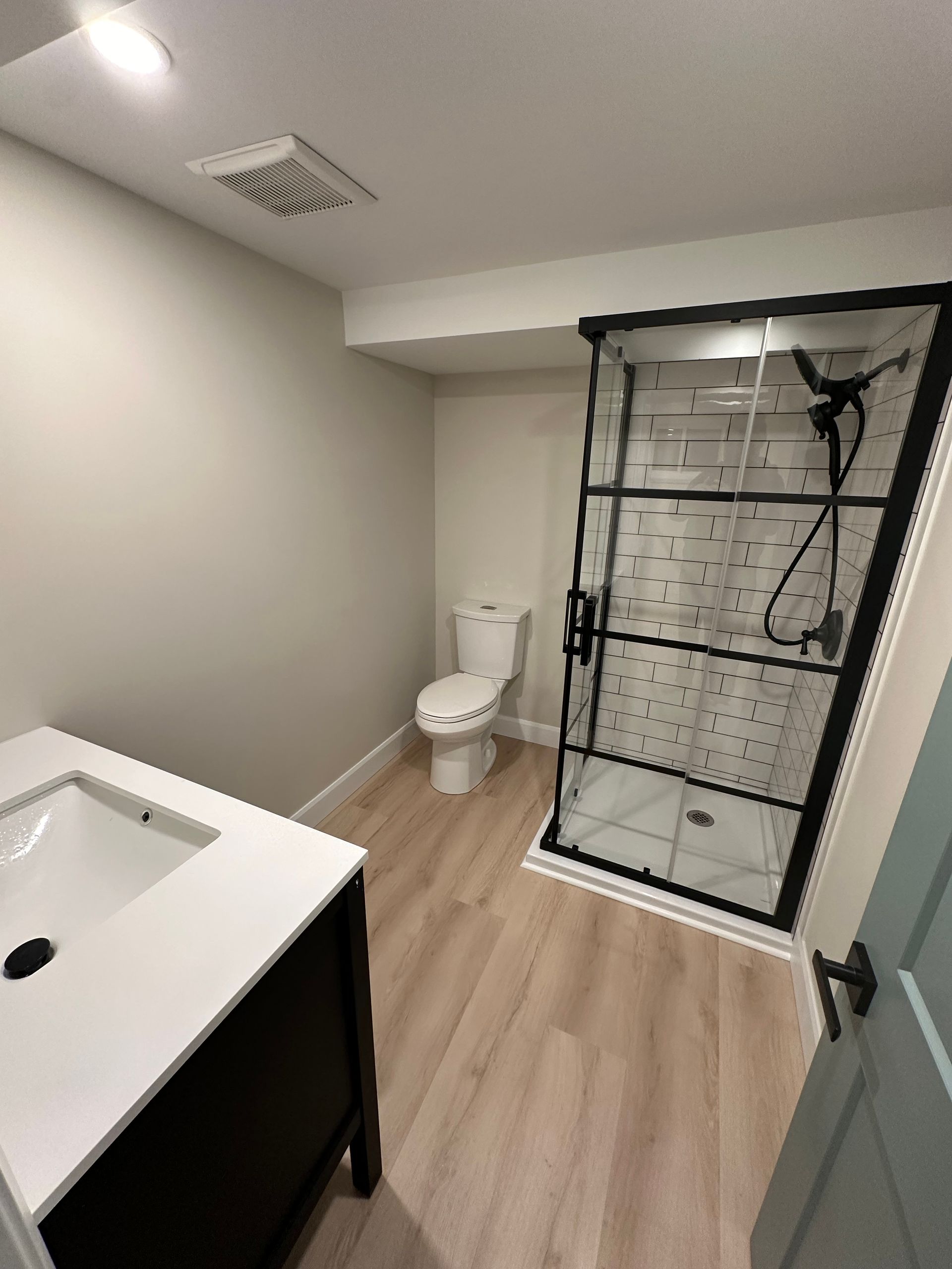 A bathroom with a toilet , sink and shower.