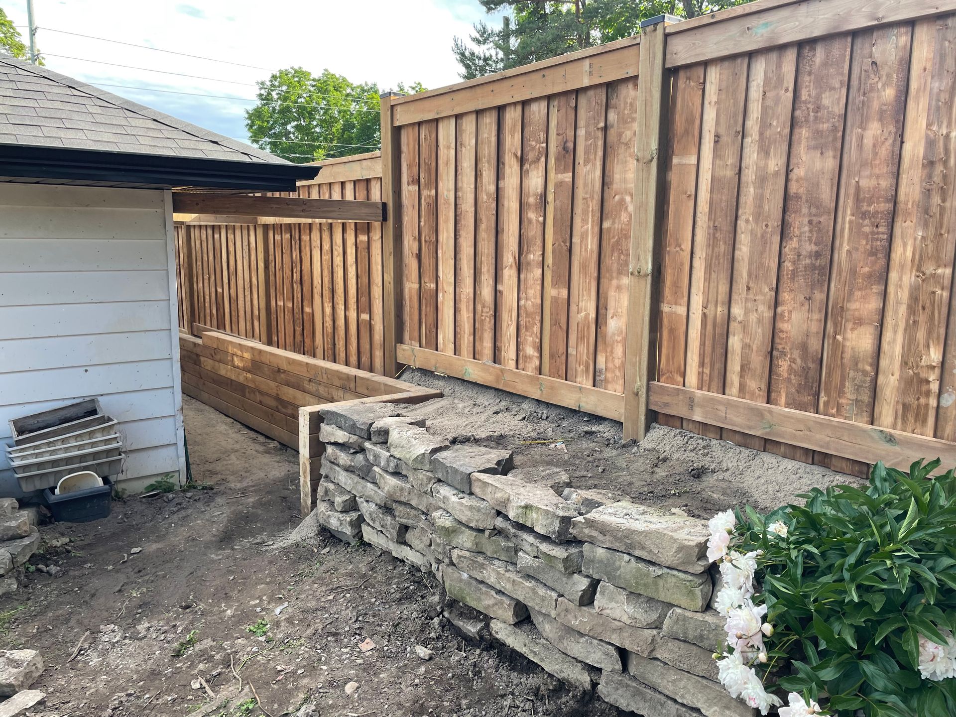 A wooden fence is being built next to a stone wall.