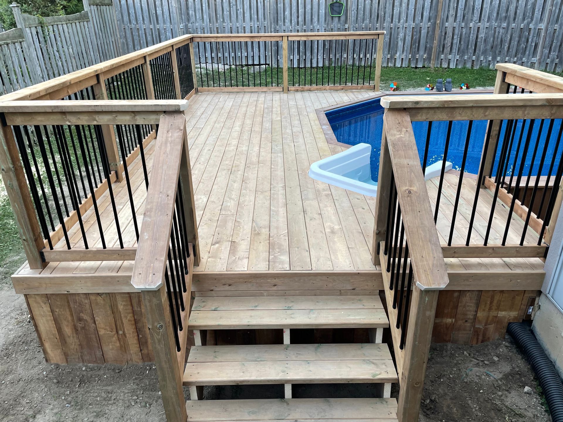 A wooden deck with stairs leading to a pool.