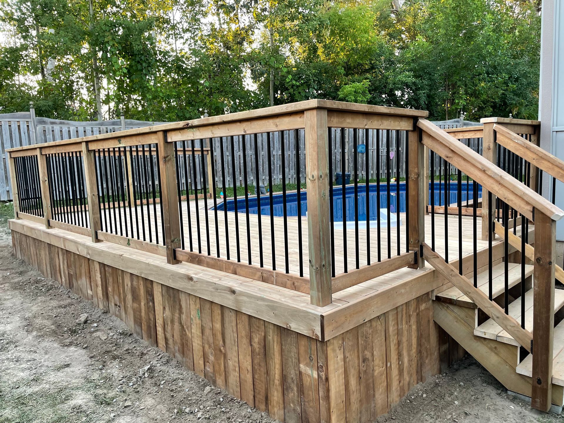 A wooden deck with stairs leading to a swimming pool.