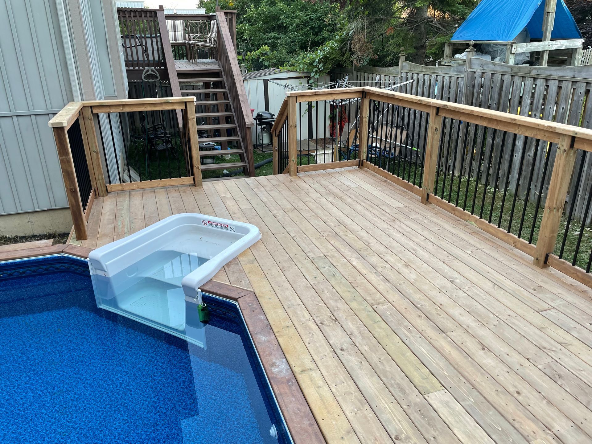 A wooden deck overlooking a swimming pool with stairs leading up to it.