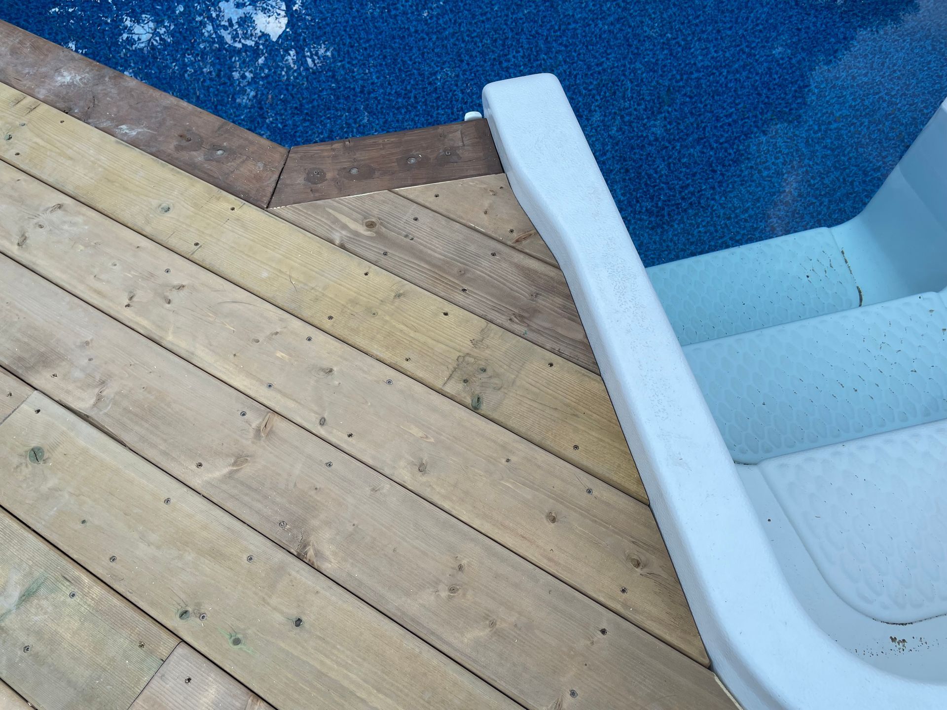 A wooden deck next to a swimming pool