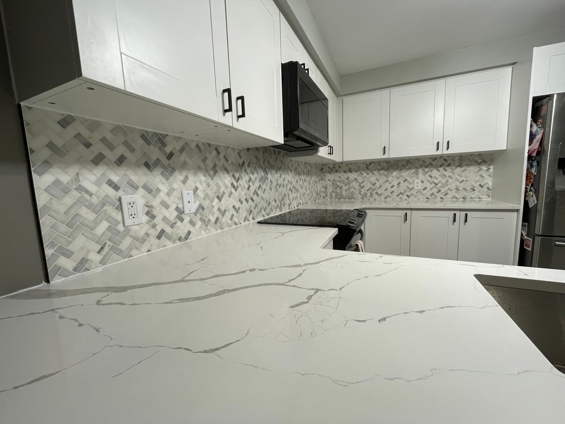 A kitchen with white cabinets and a marble counter top.