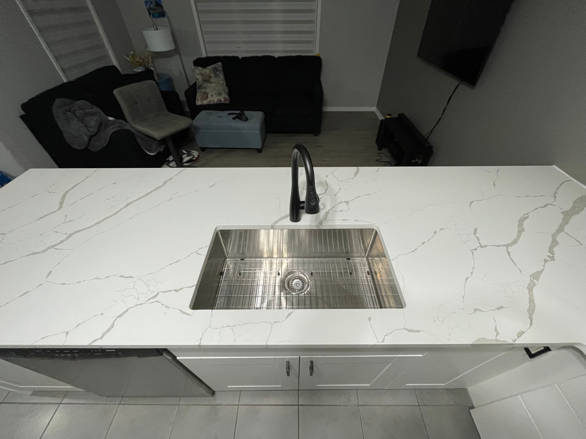 A kitchen with a stainless steel sink and a marble counter top.