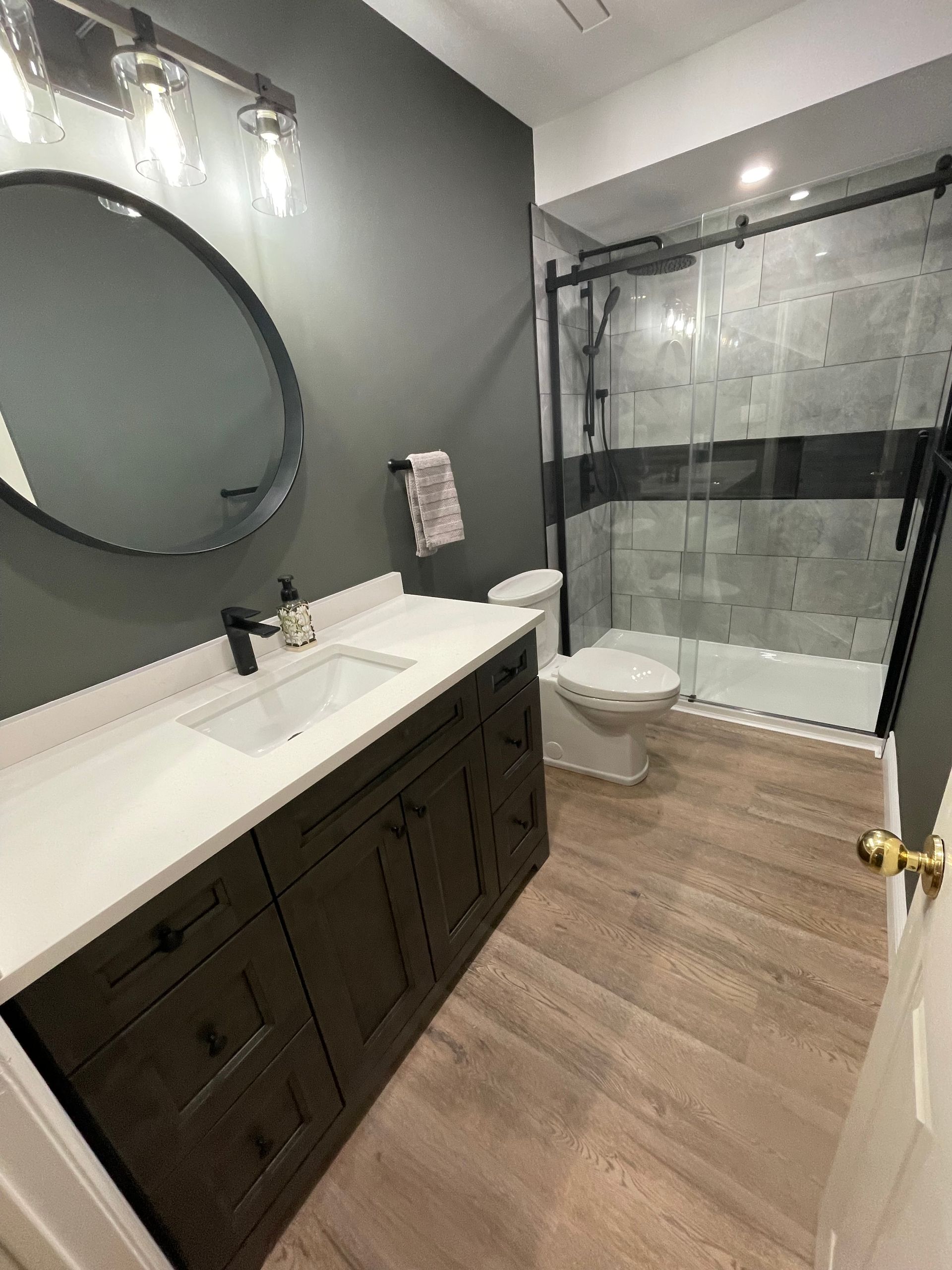A bathroom with a sink , toilet , shower and mirror.