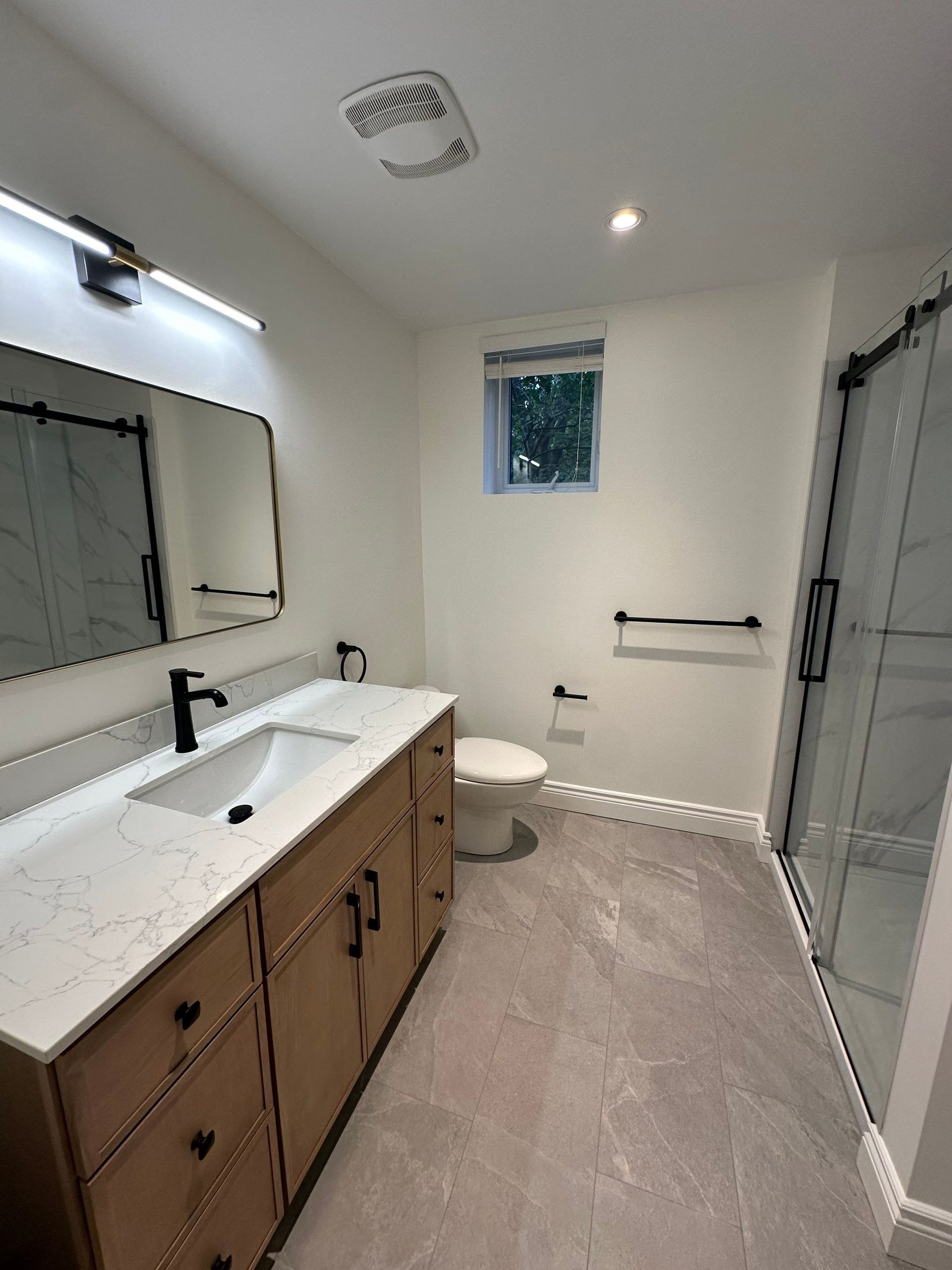 A bathroom with a sink , toilet , mirror and shower.