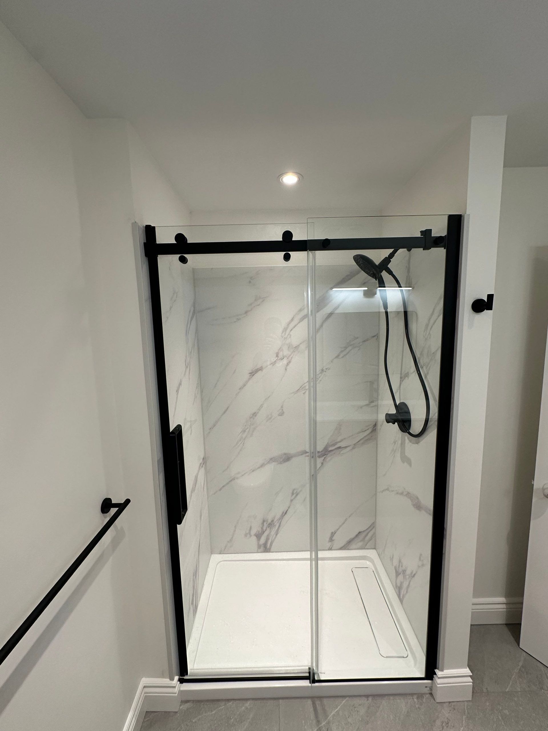 A bathroom with a sliding glass shower door and a shower head.