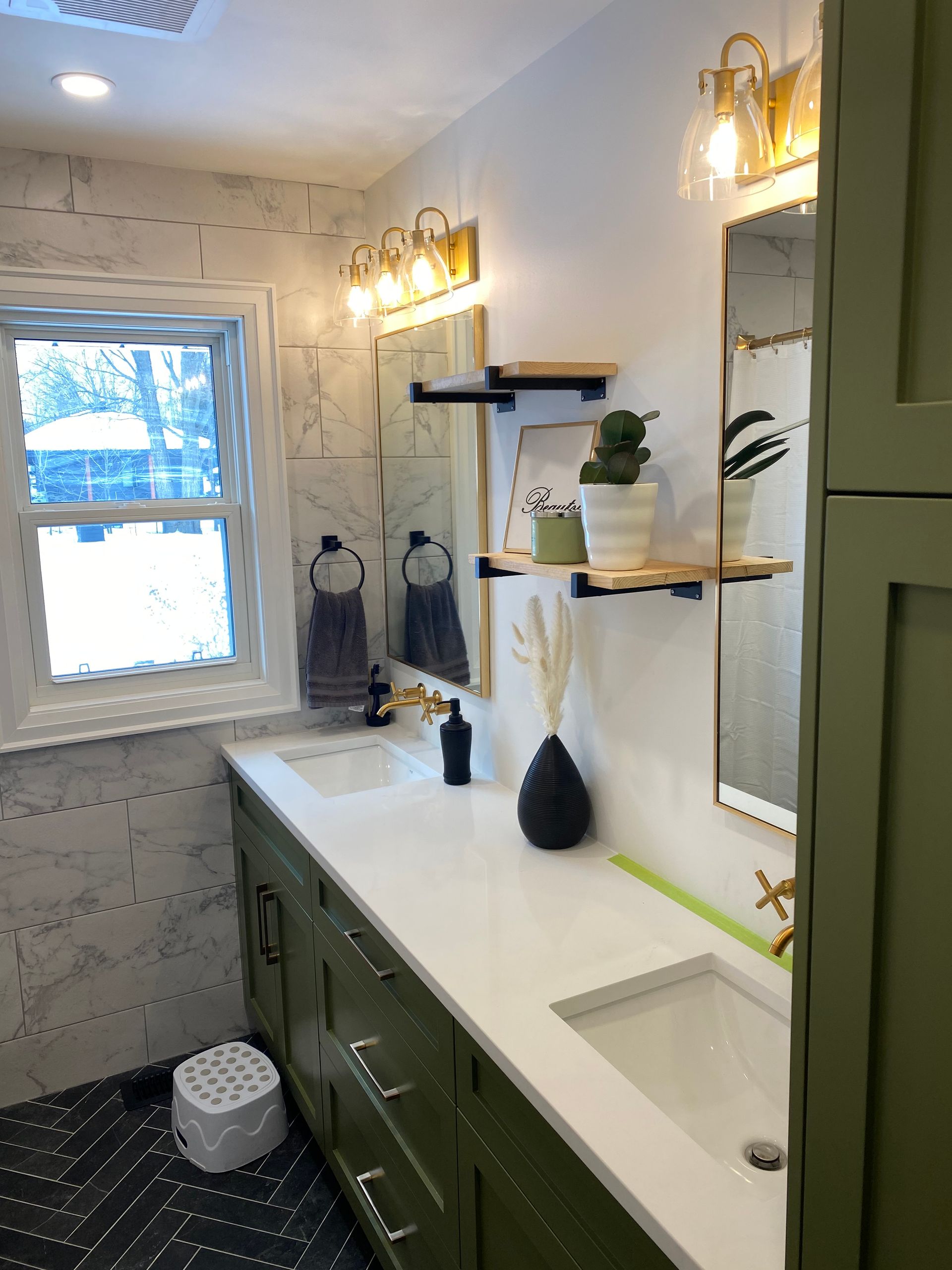 A bathroom with two sinks , a mirror and a window.