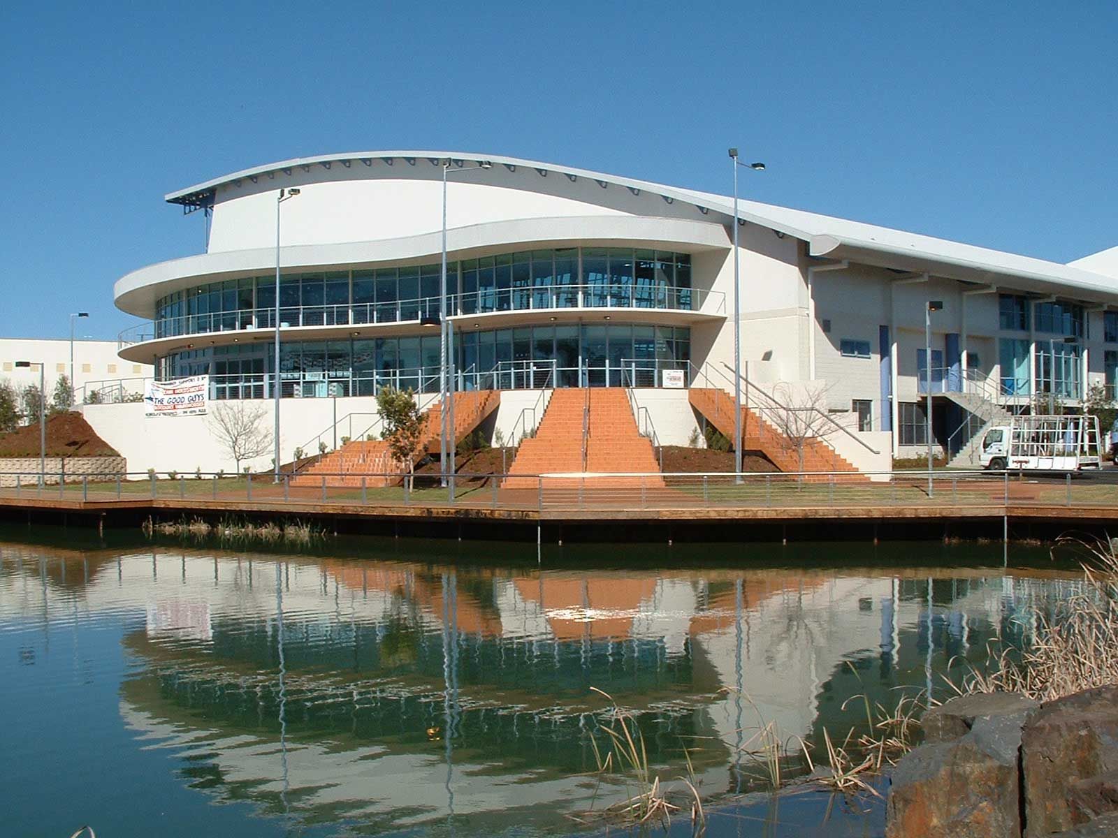 A Newly Built Stadium with Full Glass Windows and Orange Stairs — Glass Windows & Doors in Shoalhaven, NSW