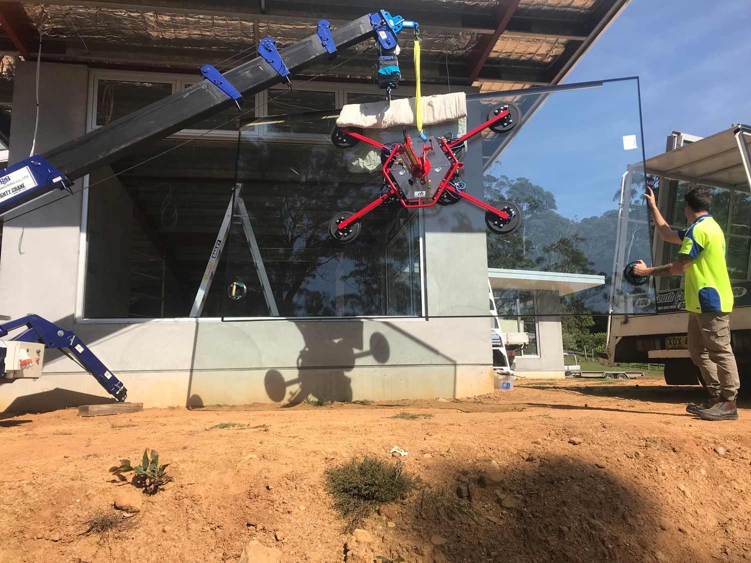 A Truck Installing Glass Wall in a House Construction — Glass Windows & Doors in Shoalhaven, NSW