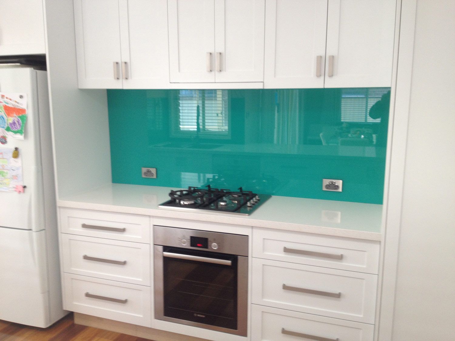 A Kitchen with a Teal Color Wall Splashback — Glass Windows & Doors in Shoalhaven, NSW