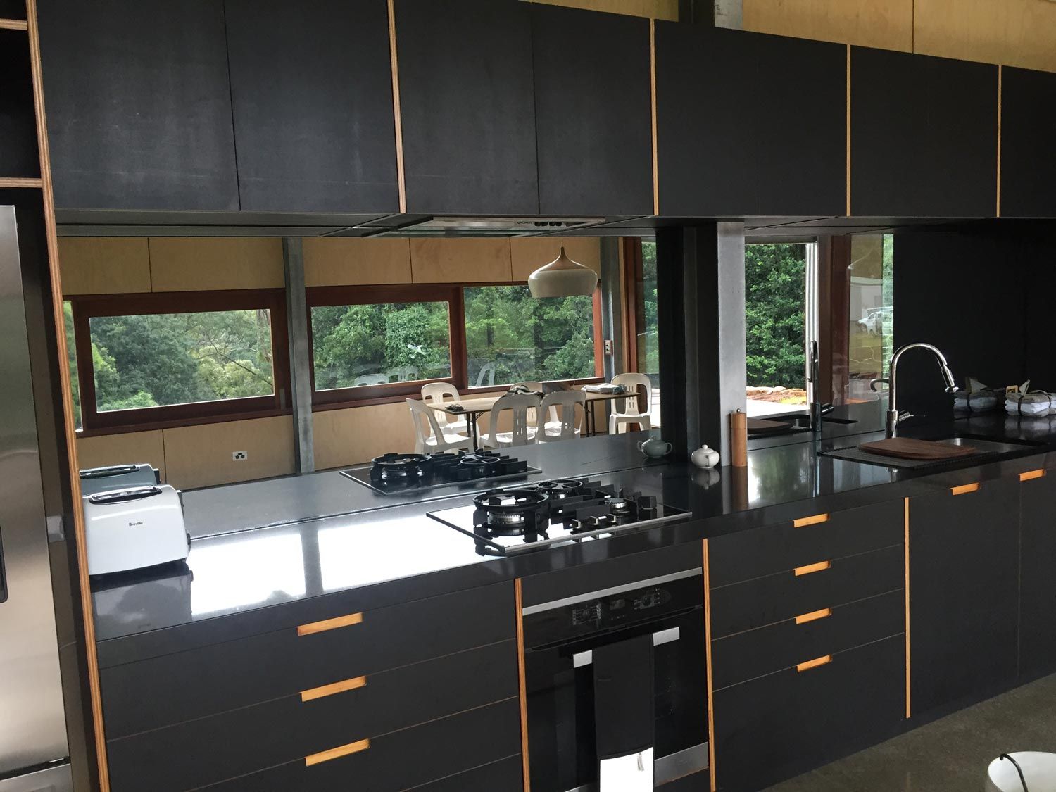 A Black Kitchen with a Mirror Splashback — Glass Windows & Doors in Shoalhaven, NSW