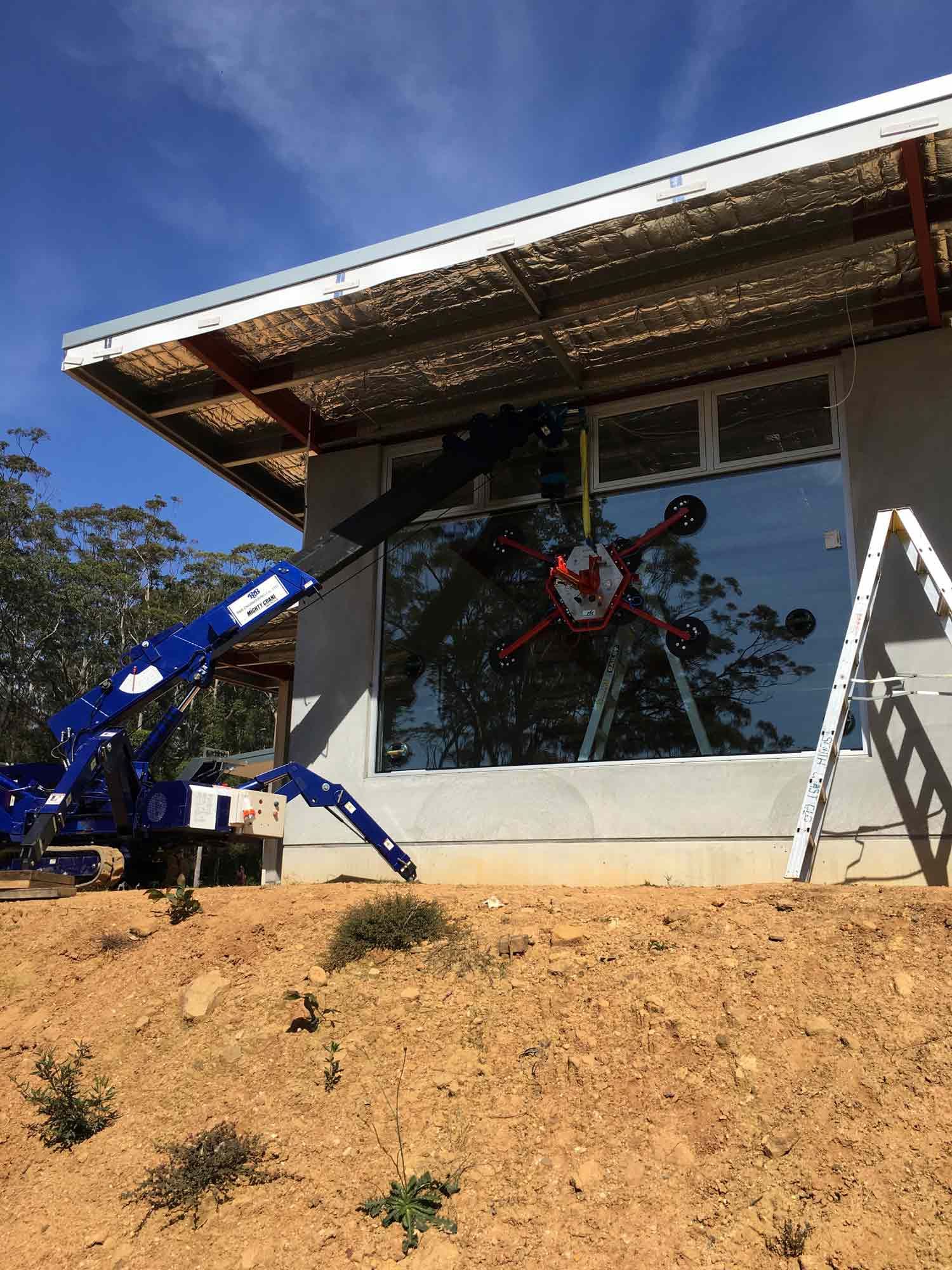 A Blue Crane Using for Glass Installation in House — Glass Windows & Doors in Shoalhaven, NSW