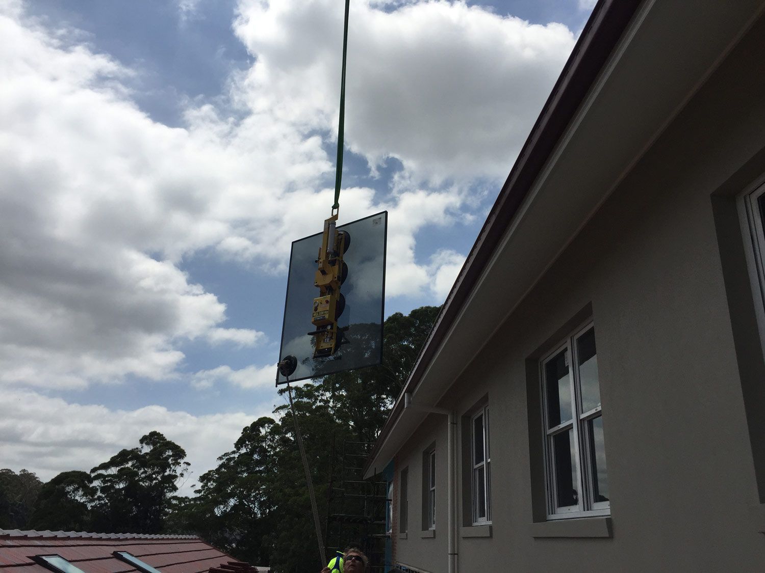 A Crane is Holding Small Window Glass — Glass Windows & Doors in Shoalhaven, NSW
