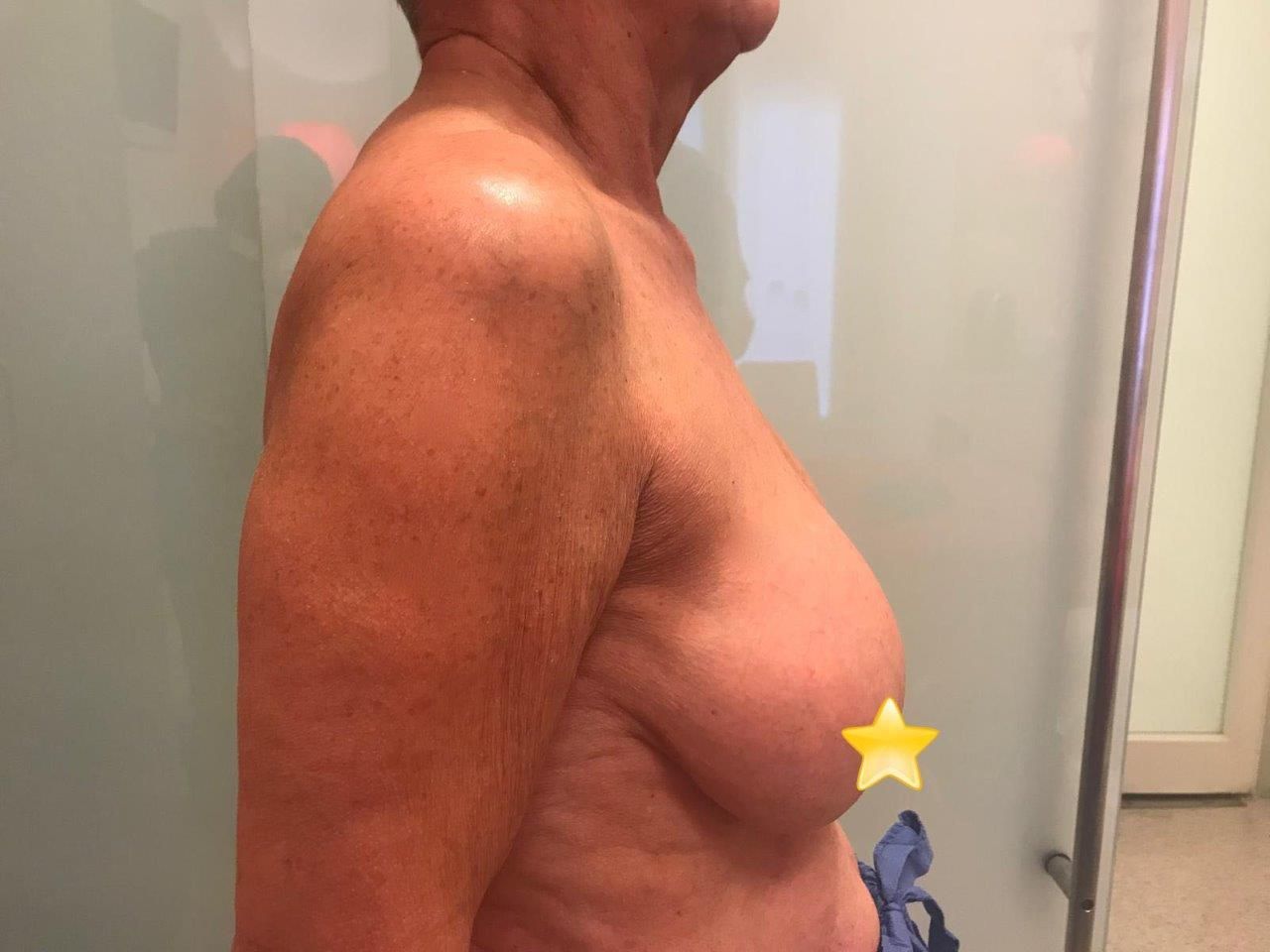 Un uomo senza camicia è in piedi davanti a una porta a vetri.