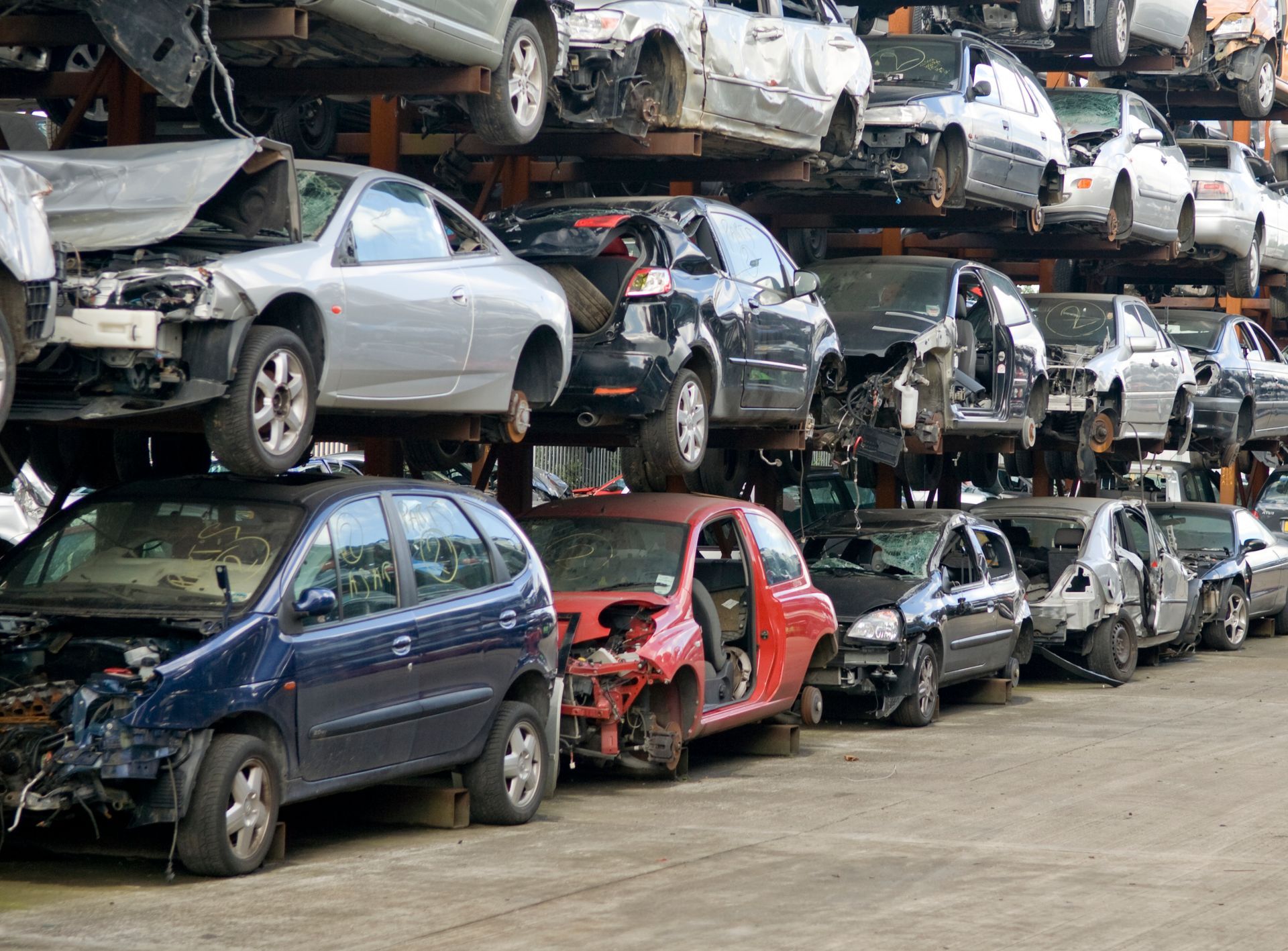 A bunch of cars are stacked on top of each other in a junkyard.