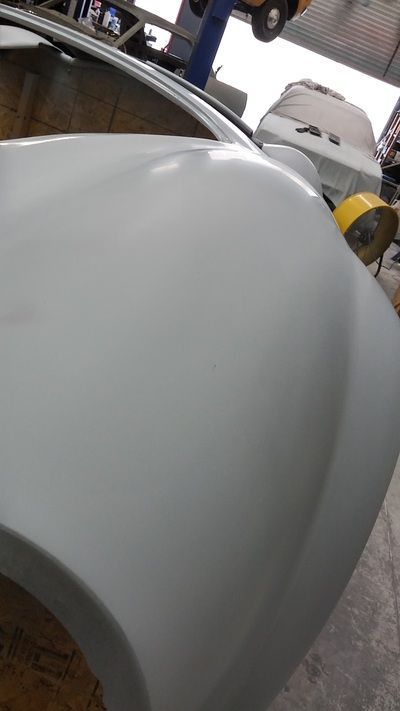 A close up of a white car fender in a garage