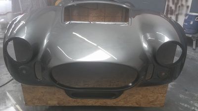 The front end of a silver sports car is sitting on a wooden box