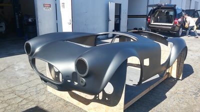 A black car body is sitting on a wooden crate