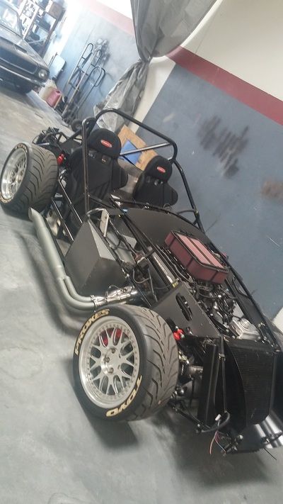 A dune buggy is being built in a garage.