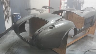 A car body is sitting on a wooden table in a garage