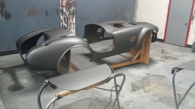 A car body is being painted in a garage