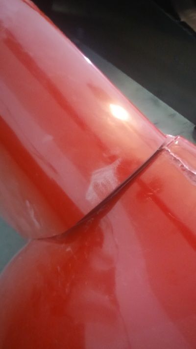 A close up of a red car hood in a garage
