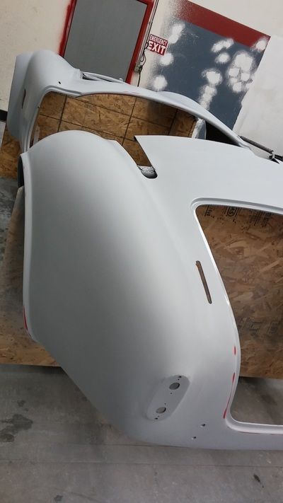 A white car is sitting on a wooden table in a garage