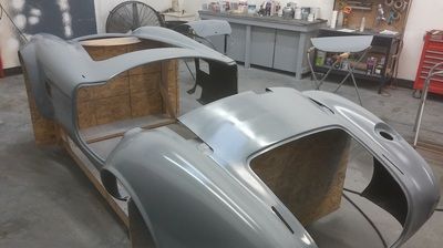 A gray car is being built in a garage
