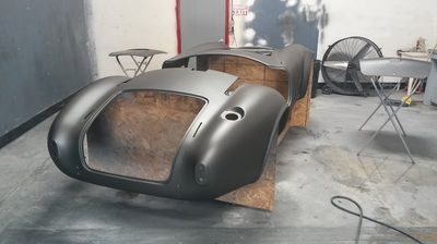 A black car body is sitting on a wooden table in a garage