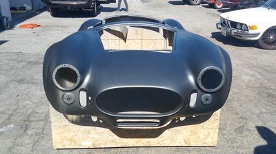 A black car is sitting on a wooden box in a parking lot