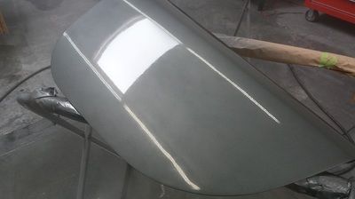 The hood of a car is being painted in a garage