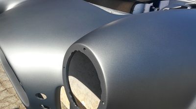 A close up of a gray car bumper with holes in it